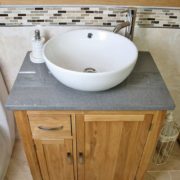 Above Closeup of Round Curved White Ceramic Basin on Grey Quartz Top Vanity Unit