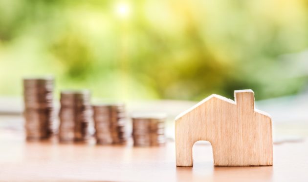 Coins Stacked & Mini Wooden House Figure infront